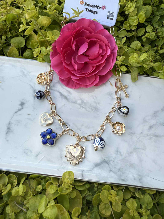 Bracelet with charms on a marble surface with a pink flower in the background