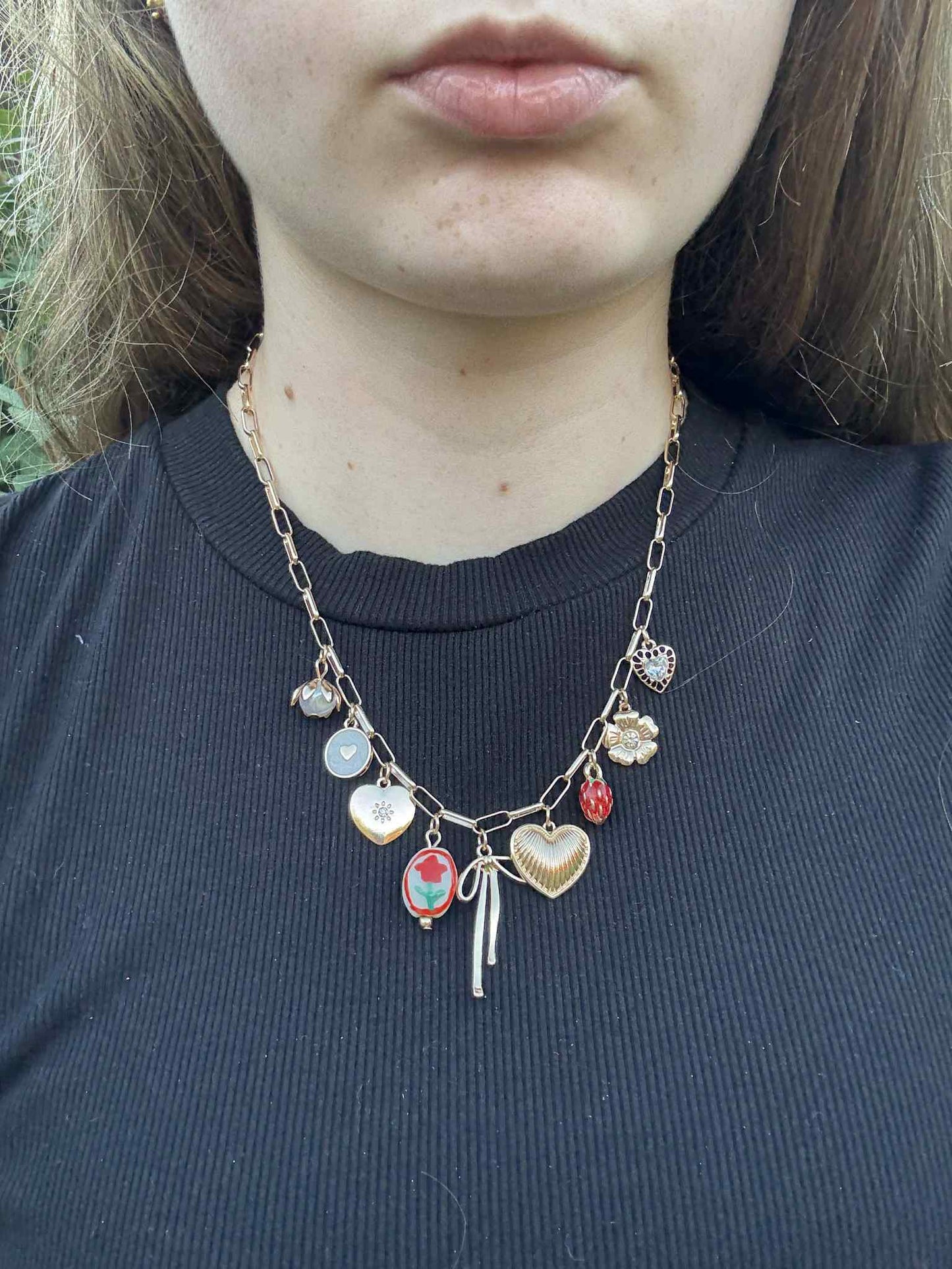 Necklace with various charms worn by a person against a dark background