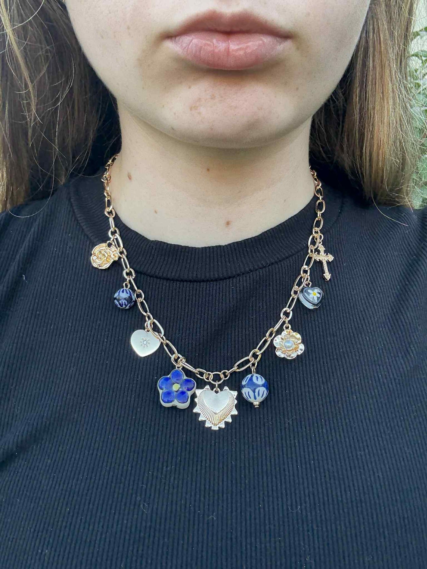 Necklace with colorful charms worn by a person against a dark background