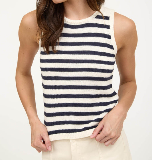 Woman wearing a vnay and white striped sleeveless top against a white background
