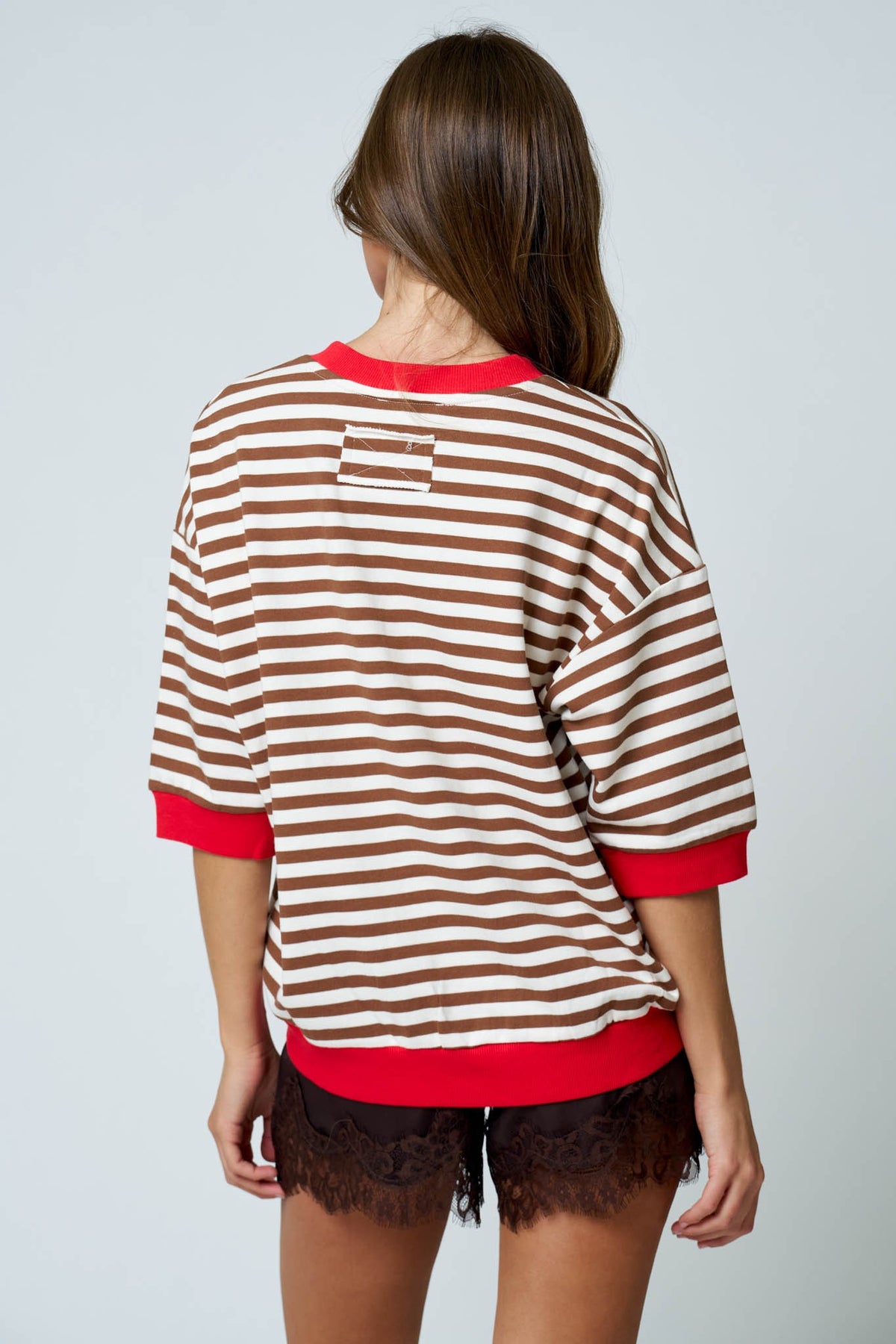 Person wearing a brown and red striped sweater with a plain background