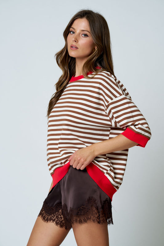 Woman wearing a striped sweater with red accents and a black skirt on a light gray background