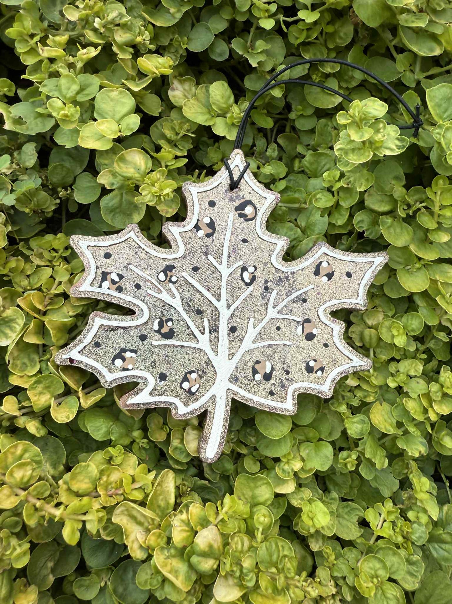 Decorative leaf freshie with black speckles on a green leaf background
