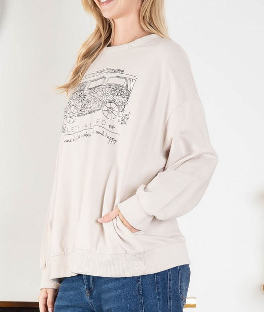 side view of woman wearing long sleeve taupe top with bus on the front