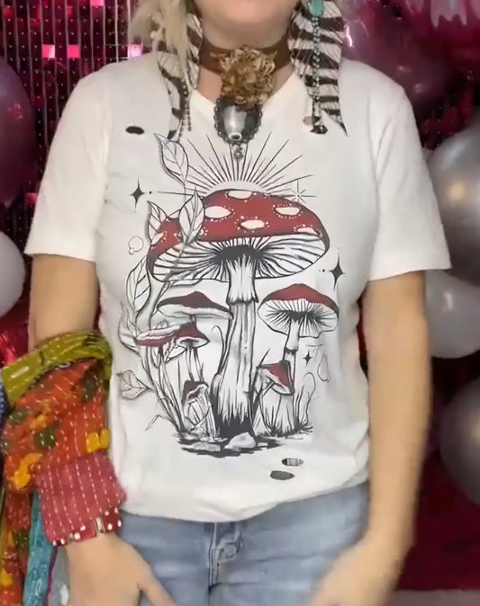 A person wearing a cream color bleached and distressed white t-shirt with a mushroom screen print design.
