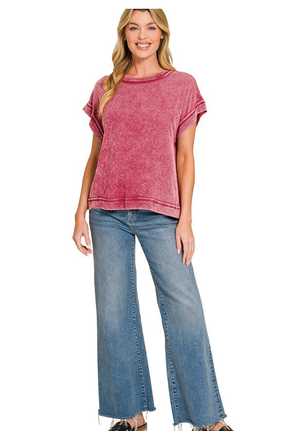 Woman wearing a cabernet ribbed top and blue jeans on a white background