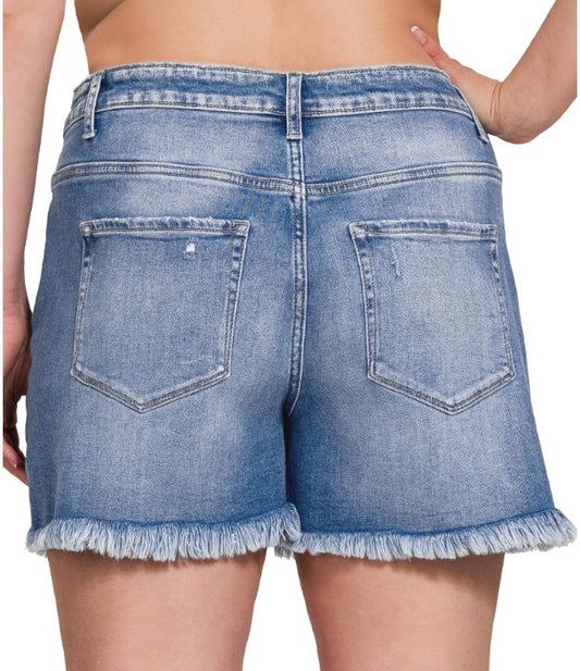 Blue denim shorts with frayed hem on a white background