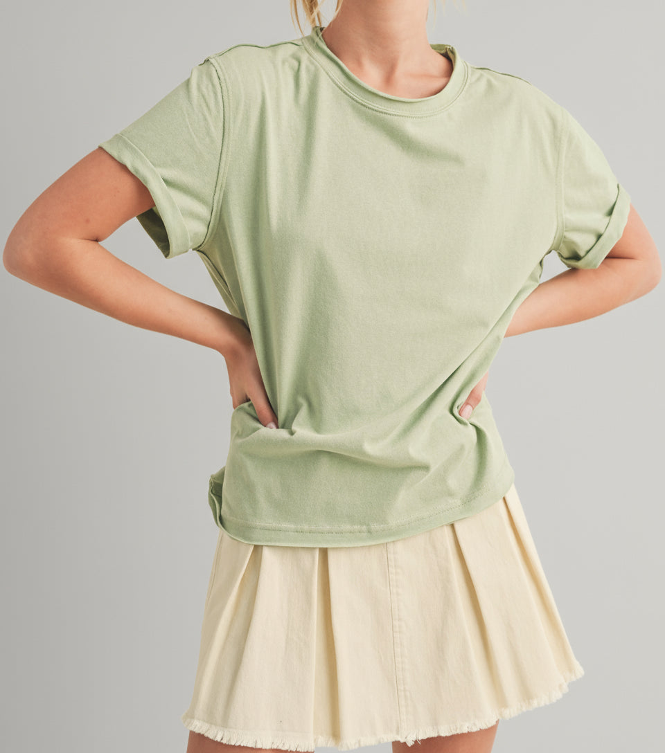 Woman wearing a light green oversized t-shirt and beige skirt on a beige background