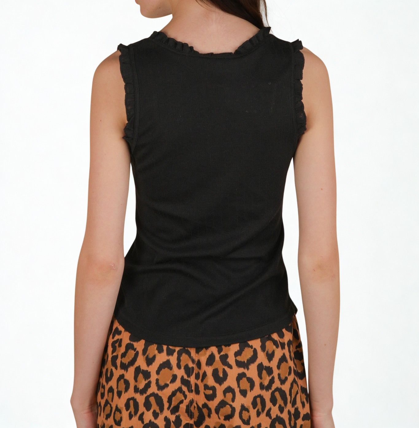 woman wearing a black ruffle trim tank top against a white background. Back view