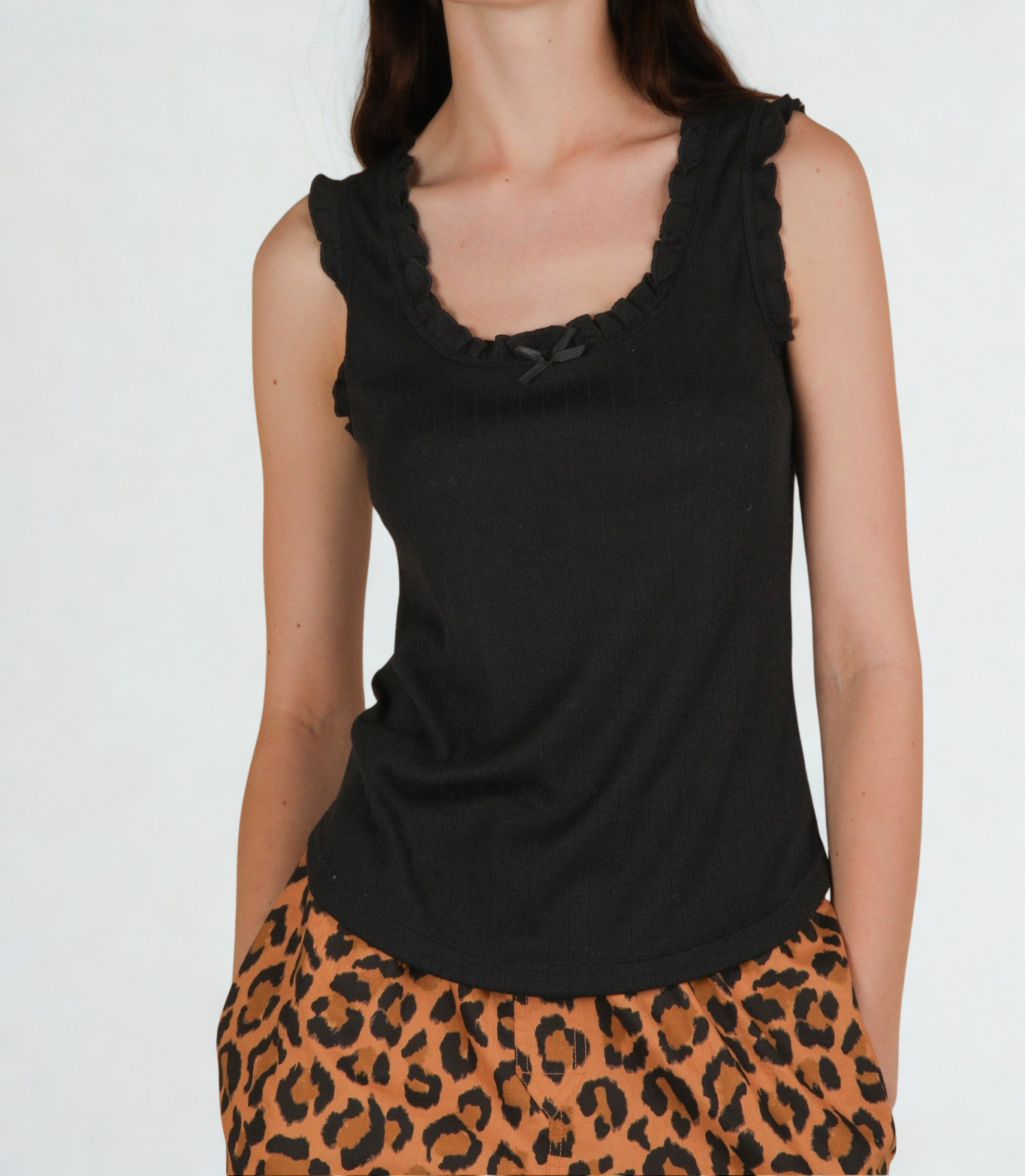 person wearing black ruffle trim tank top on a white background