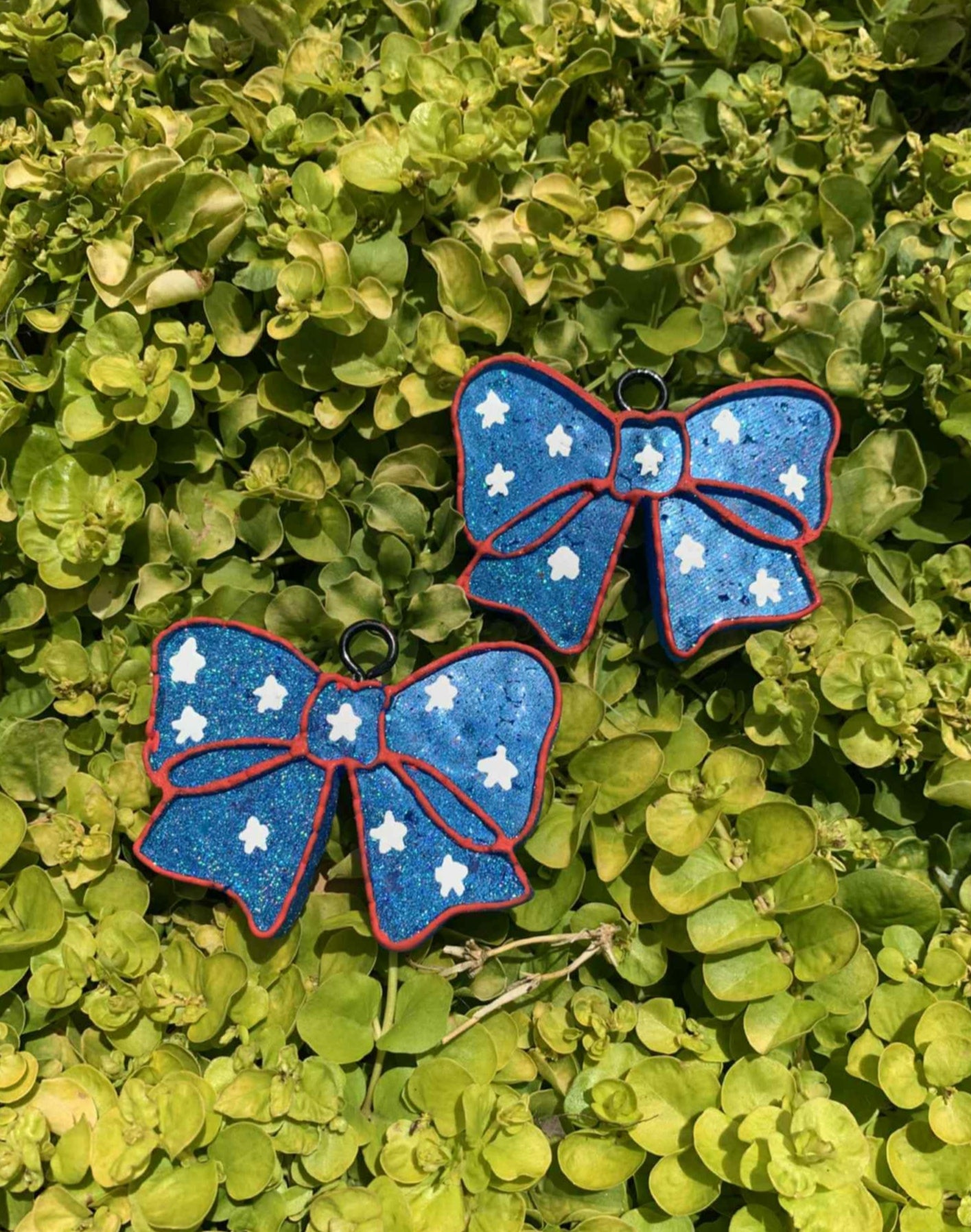 Two blue bow air fresheners with white stars on a green leafy background