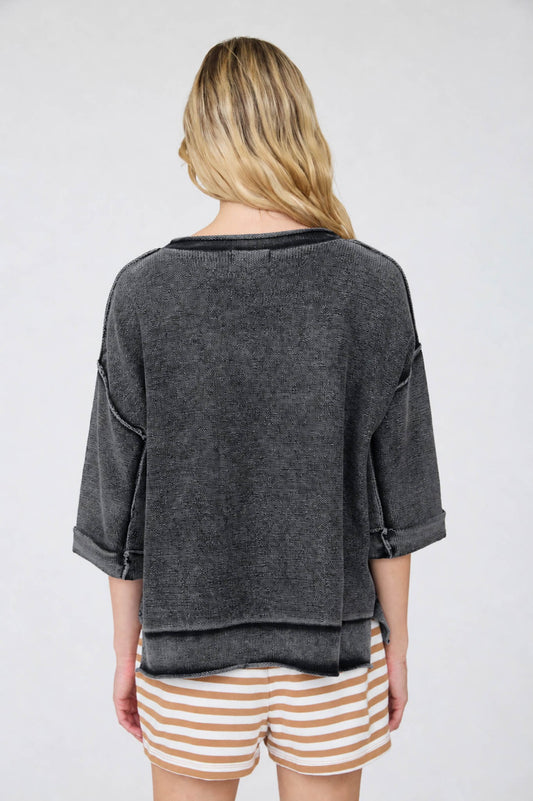 Person wearing a dark gray oversized shirt and striped shorts on a white background