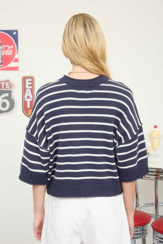 Person wearing a navy and white striped sweater with a retro sign in the background