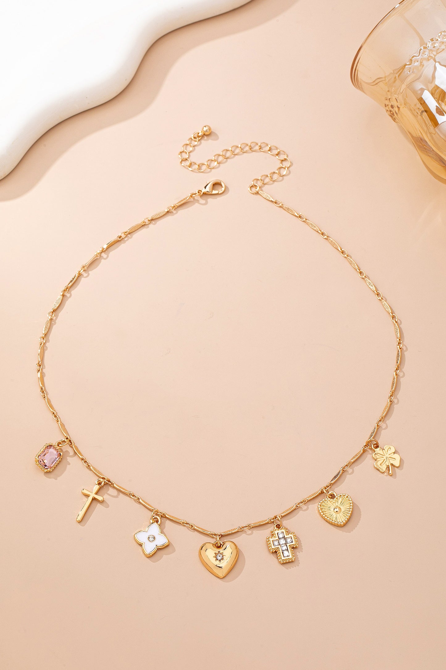 Gold necklace with various charms on a beige background