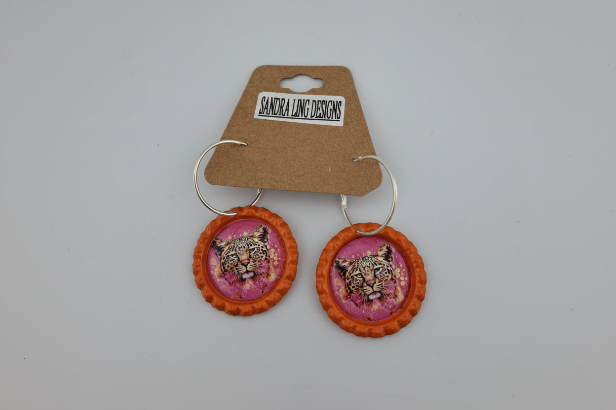 Earrings with animal print design on a pink background, displayed on a Sandra Ling Designs card.