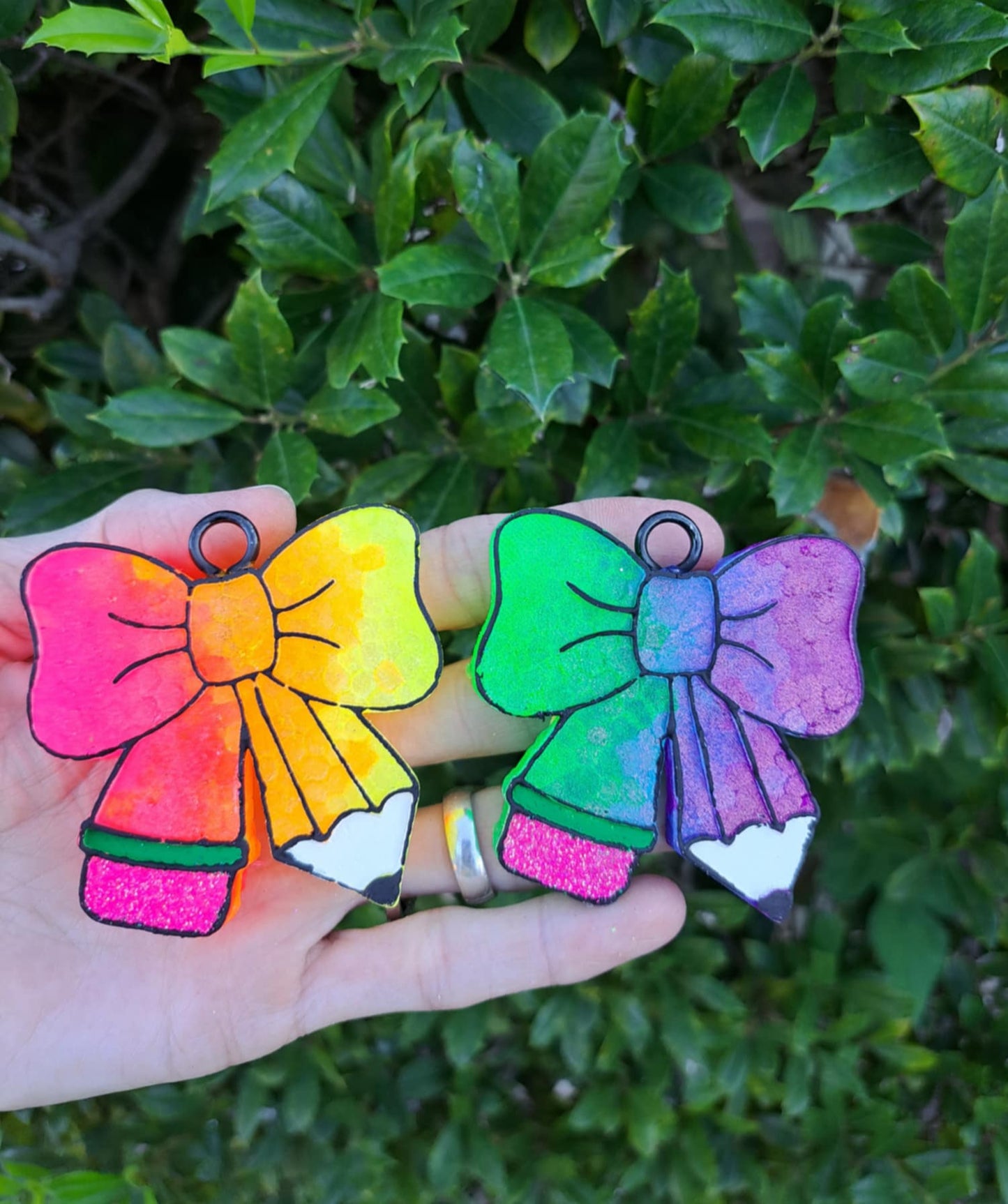 Two colorful bow-shaped freshies held in front of a green leafy background