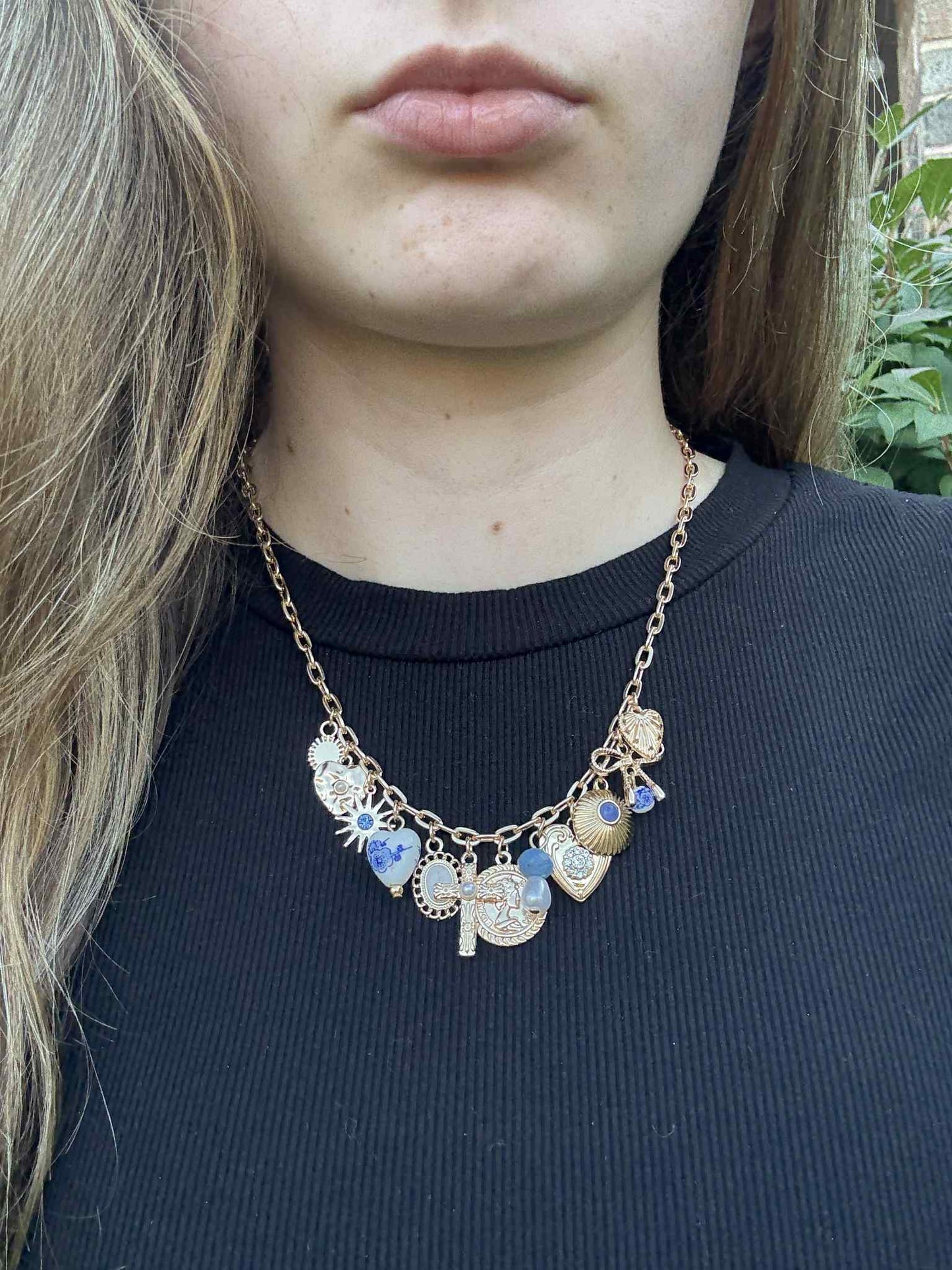 Necklace with decorative pendants worn by a person against a blurred natural background