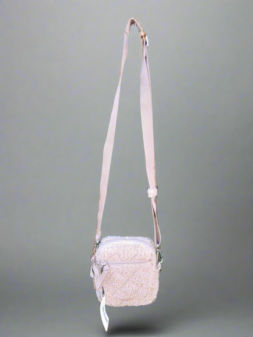 Beige crossbody bag with a strap on a neutral background