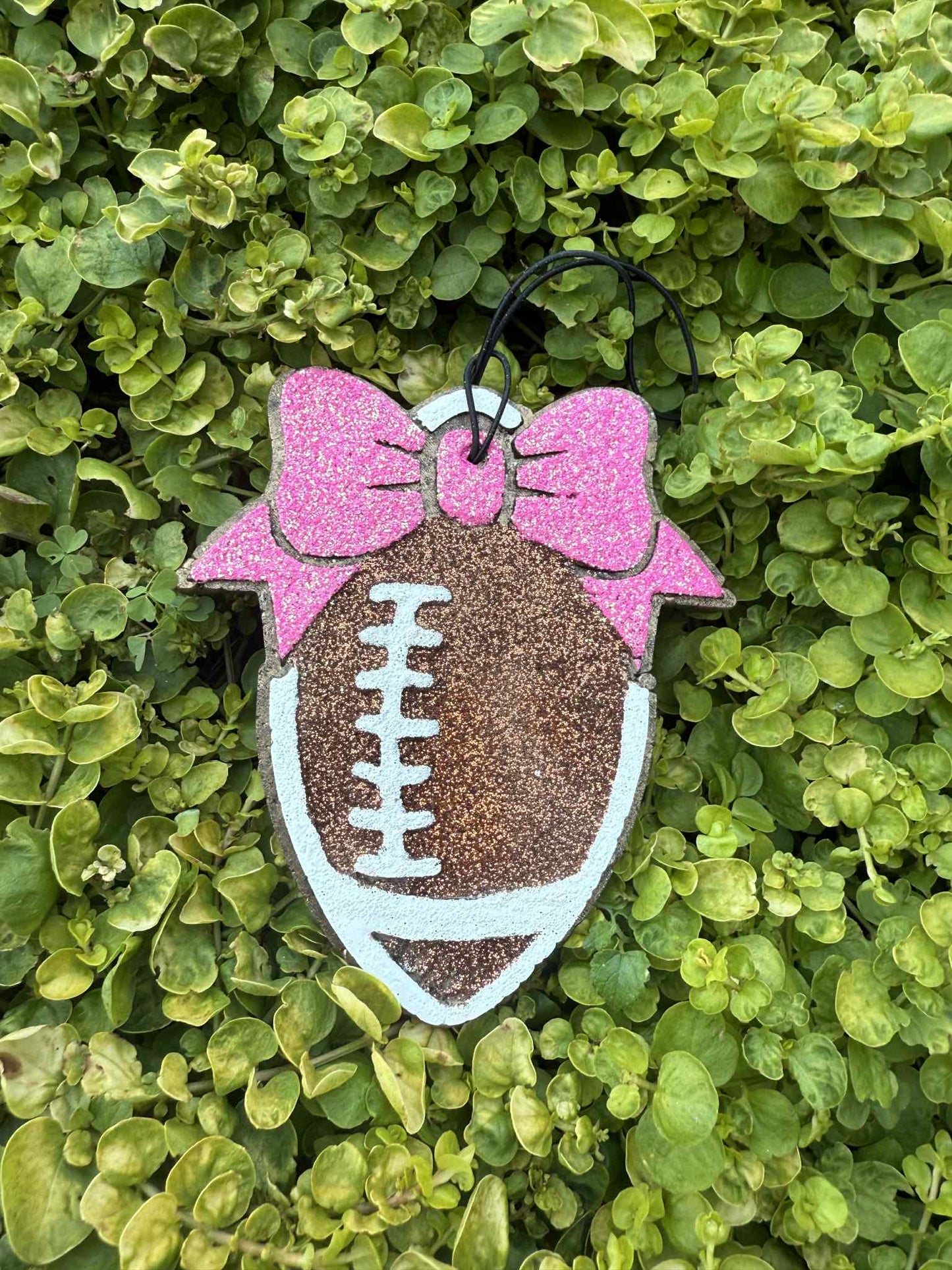 football air freshener on string with pink bow. Greenery background