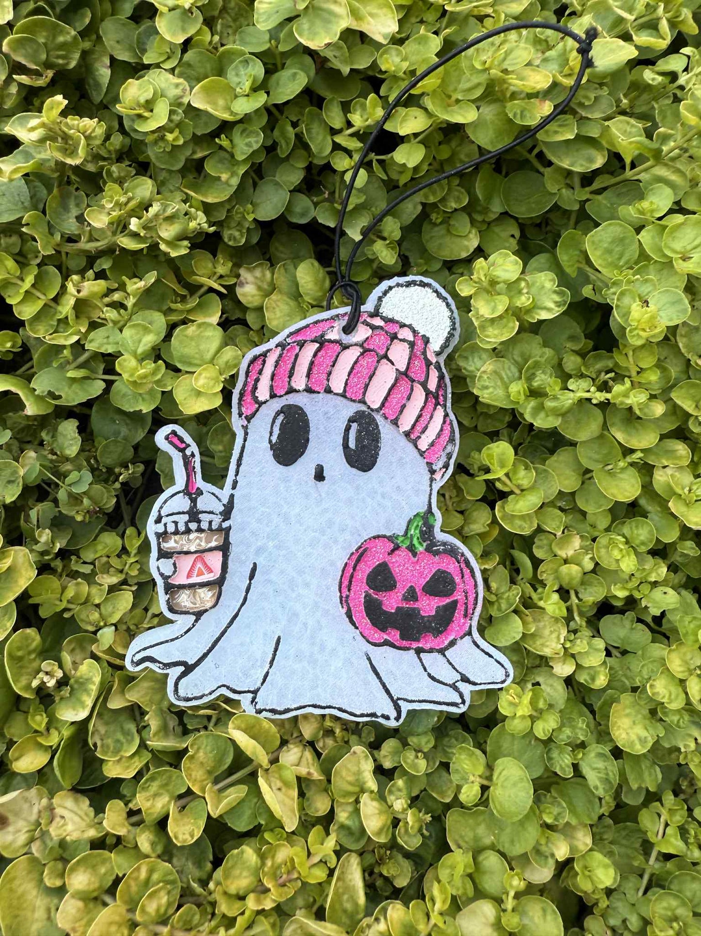 ghost freshie holding drink and pumpkin. greenery background