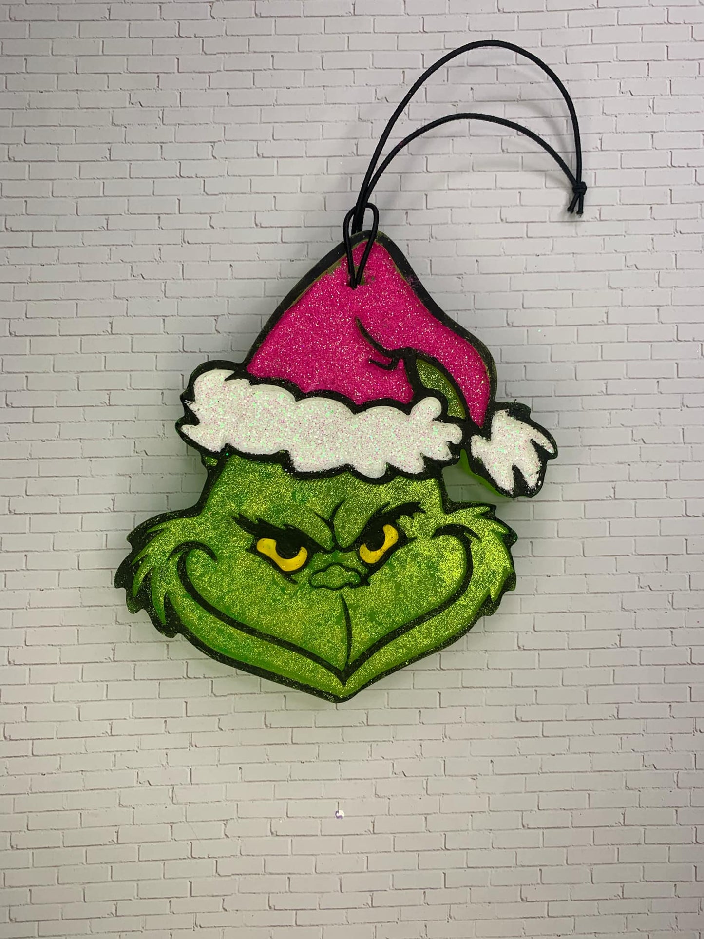 A hanging air freshener designed to look like a character wearing a pink Santa hat on a white background