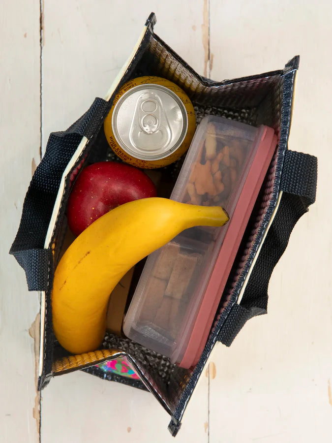 Small bag with a banana, can, and container on a wooden surface