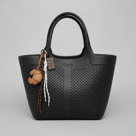 Keychain charm with chocolate bar, croissant, and rope on a black bag with neutral lighting