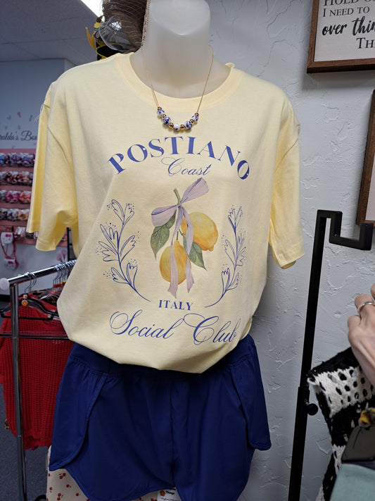 buttercream tee with lemon on a hanging display in a store wearing blue shorts