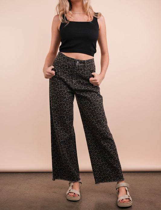 person wearing leaopar jeans on a cream background