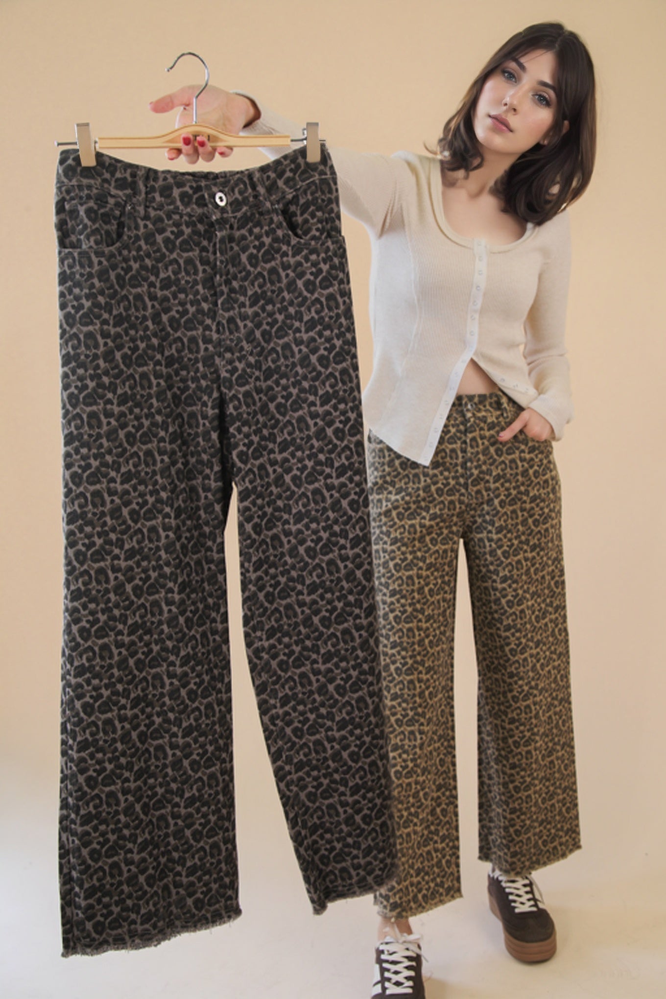 Woman holding a hanger with patterned pants next to herself on a plain background