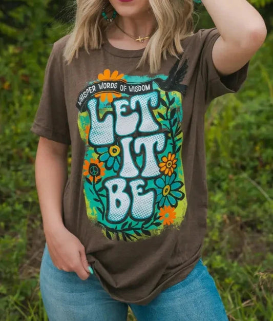 A person wearing a brown t-shirt with the text 'Let It Be' and floral design on it.
