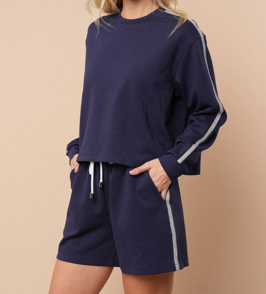Navy blue sweatshirt and shorts set with white trim on a beige background