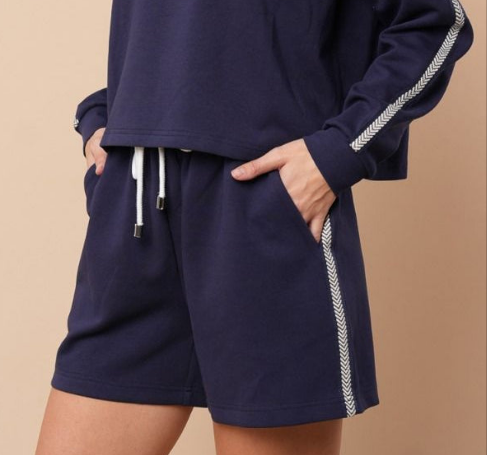 Navy knit shorts with white trim down the side. Beige background
