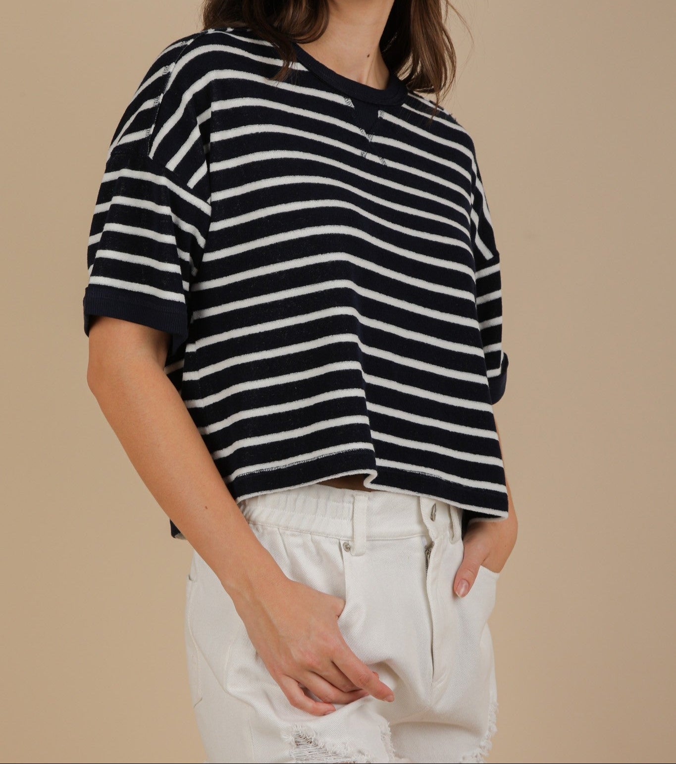 Woman wearing a navy and white striped shirt against a beige background