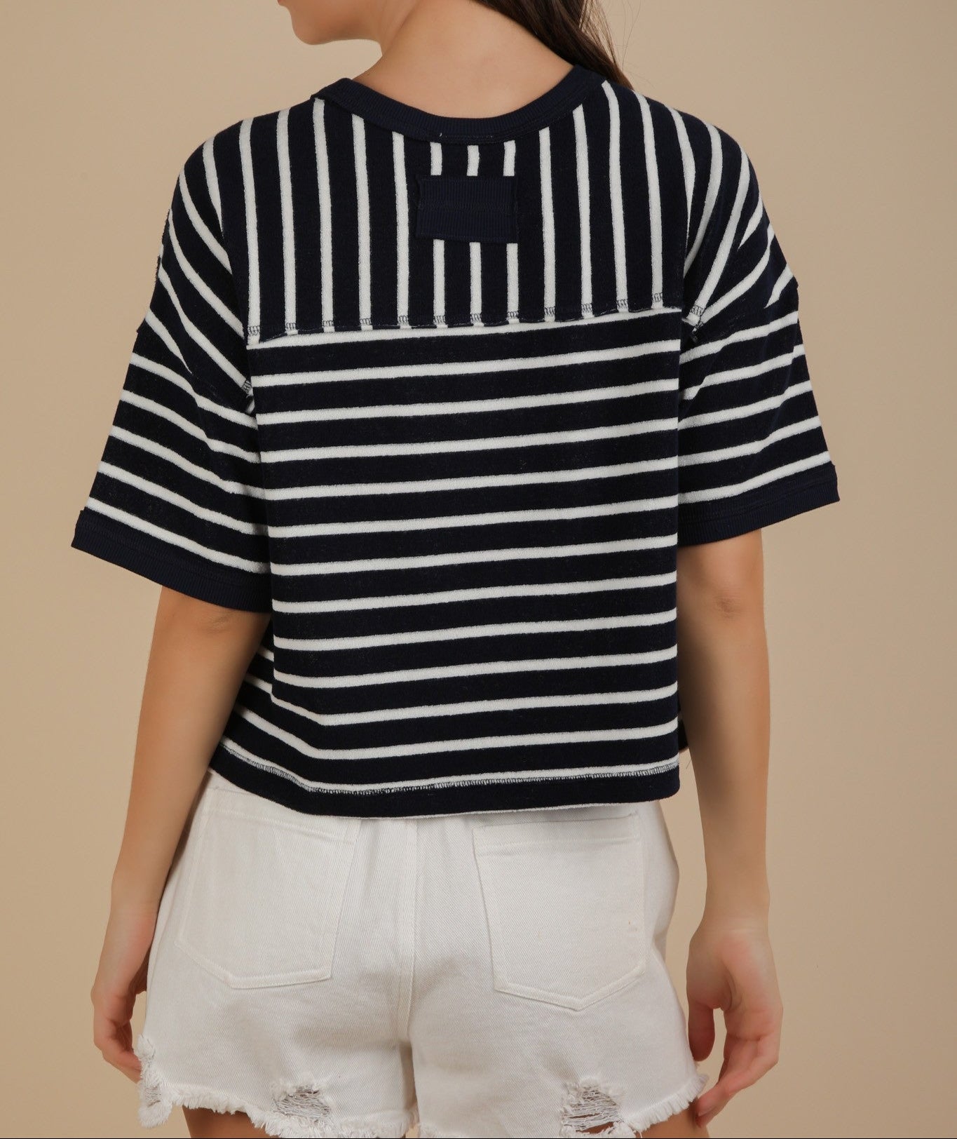 Person wearing a navy and white striped shirt with a plain background