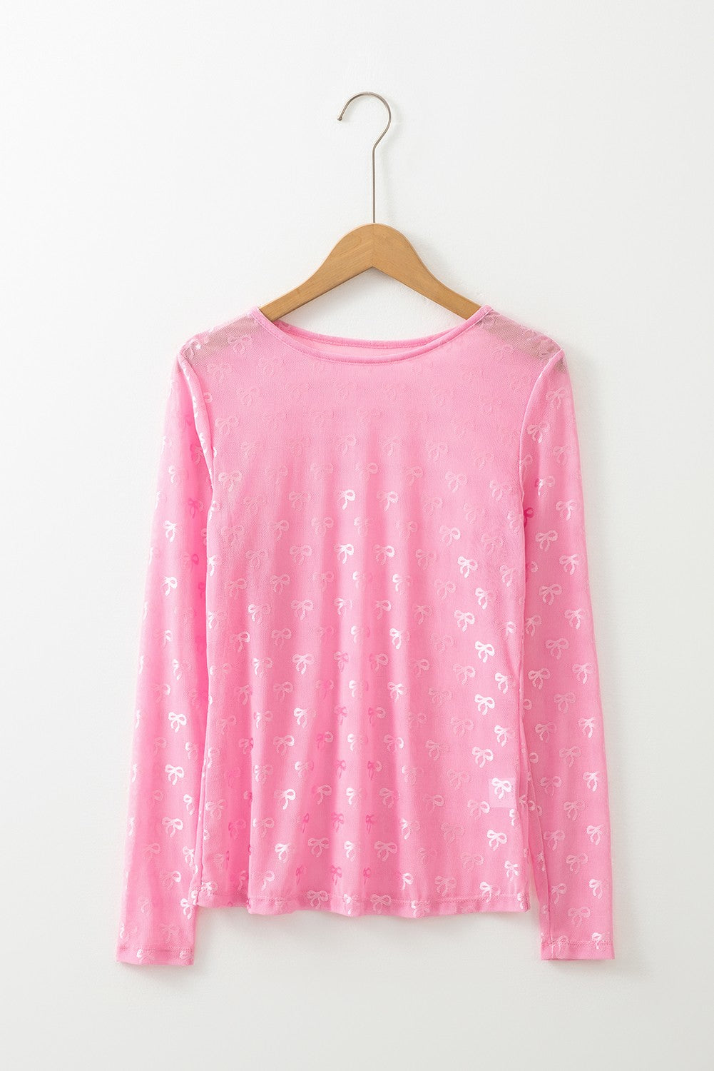 A pink bow print lace mesh top displayed on a wooden hanger against a white background.