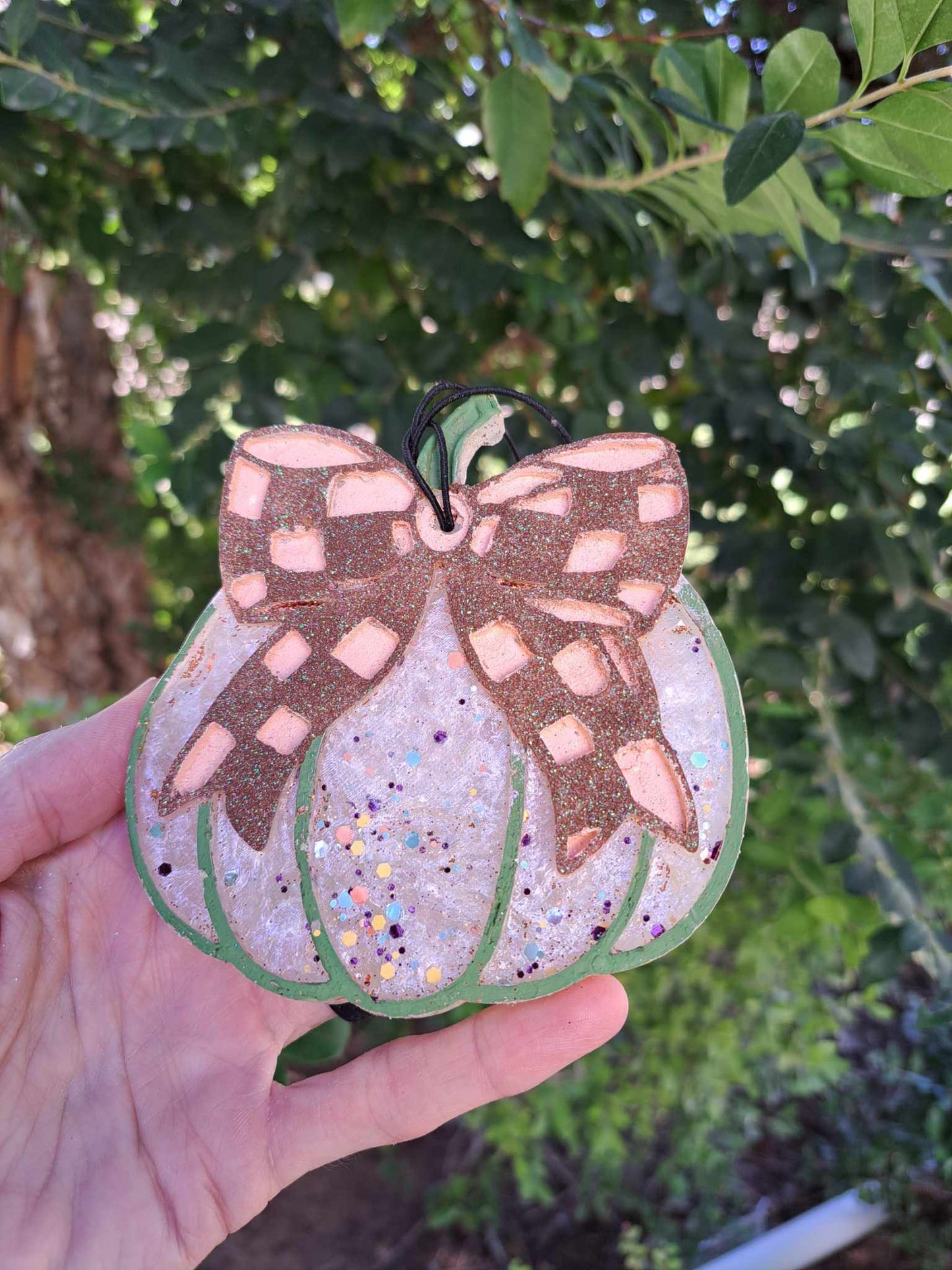 hand holding a white pumpkin shaped freshie with brown checkered bow