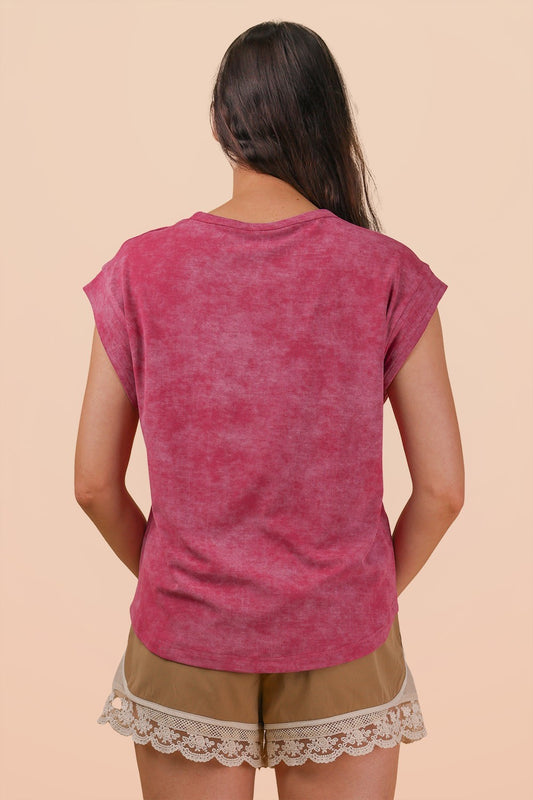 Woman wearing a pink t-shirt and beige shorts with lace trim on a beige background