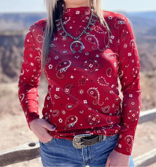 A person wearing a red long-sleeved mesh top with a bandana pattern, paired with blue jeans.