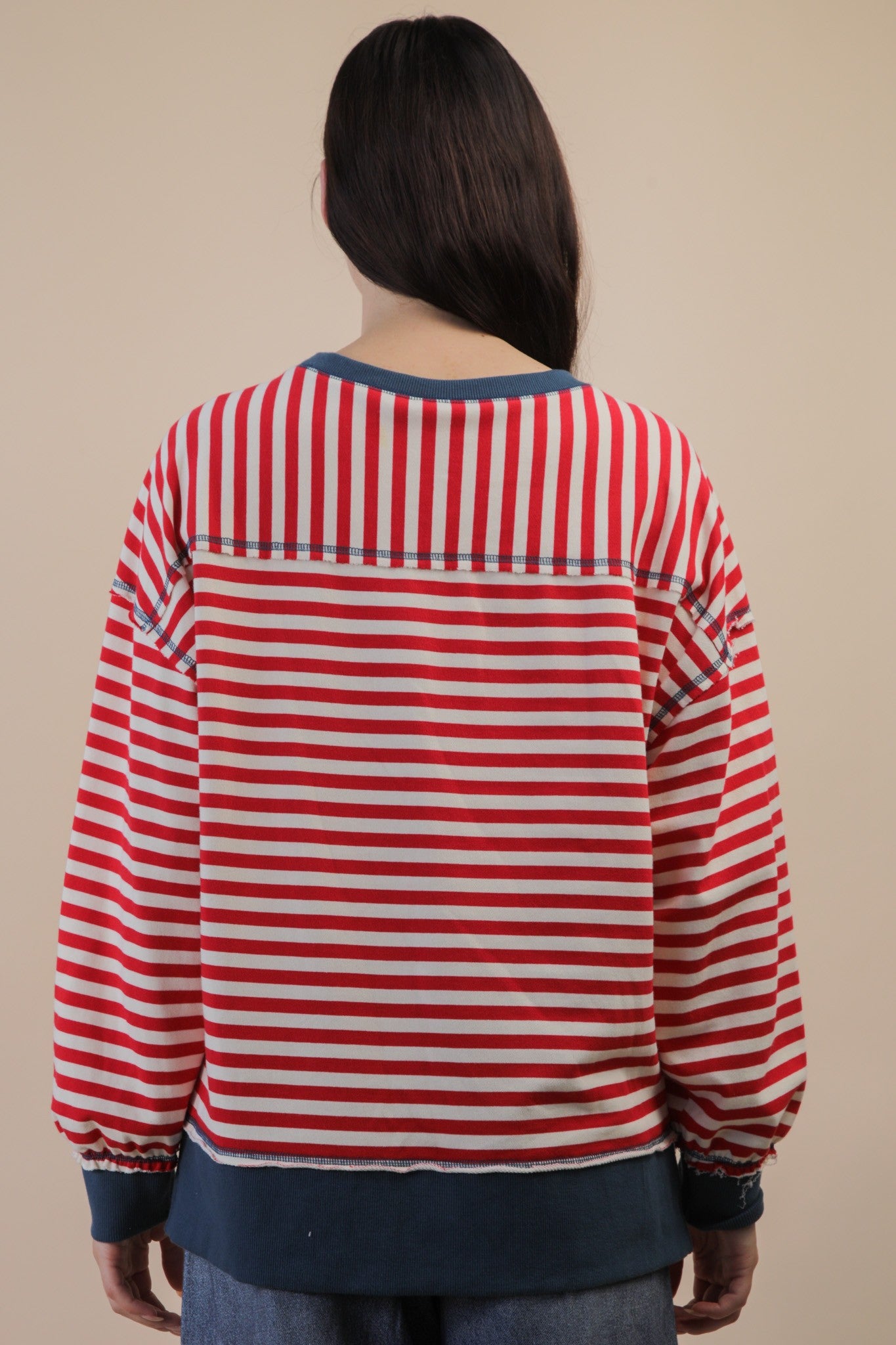 back of person wearing red and cream striped long sleeve top with blue trim