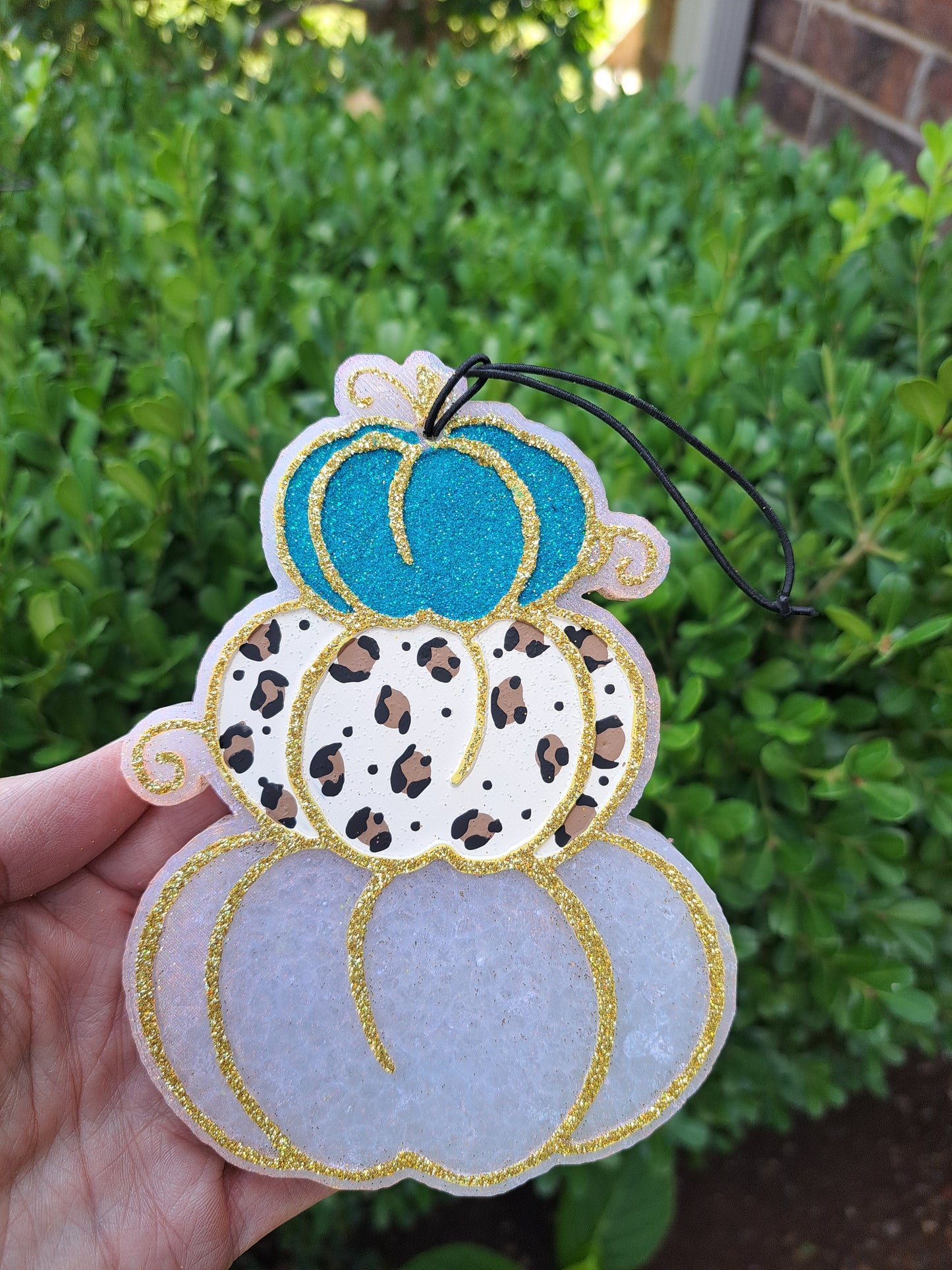 Decorative freshie with leopard print and turquoise design pumpkins held against a green background