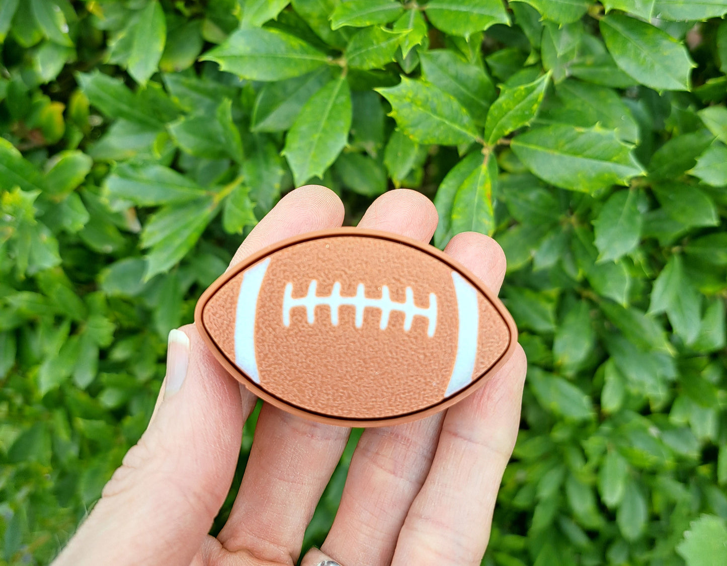 hand holding a 3d football clicker. Green background