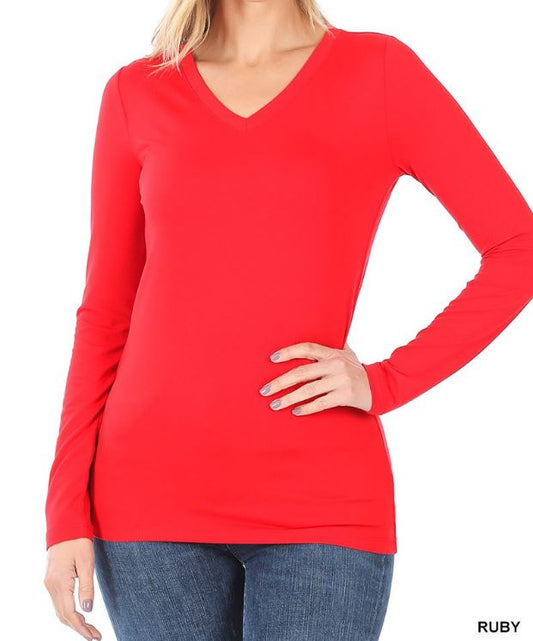 A woman wearing a ruby red microfiber V-neck long sleeve top, paired with blue jeans. The image shows the top in a flat, solid color without any visible texture or sheen. White background.