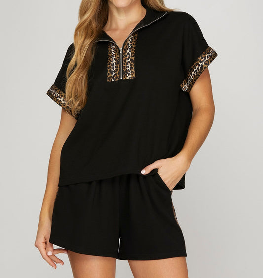 Woman wearing a black outfit with leopard print accents on a white background