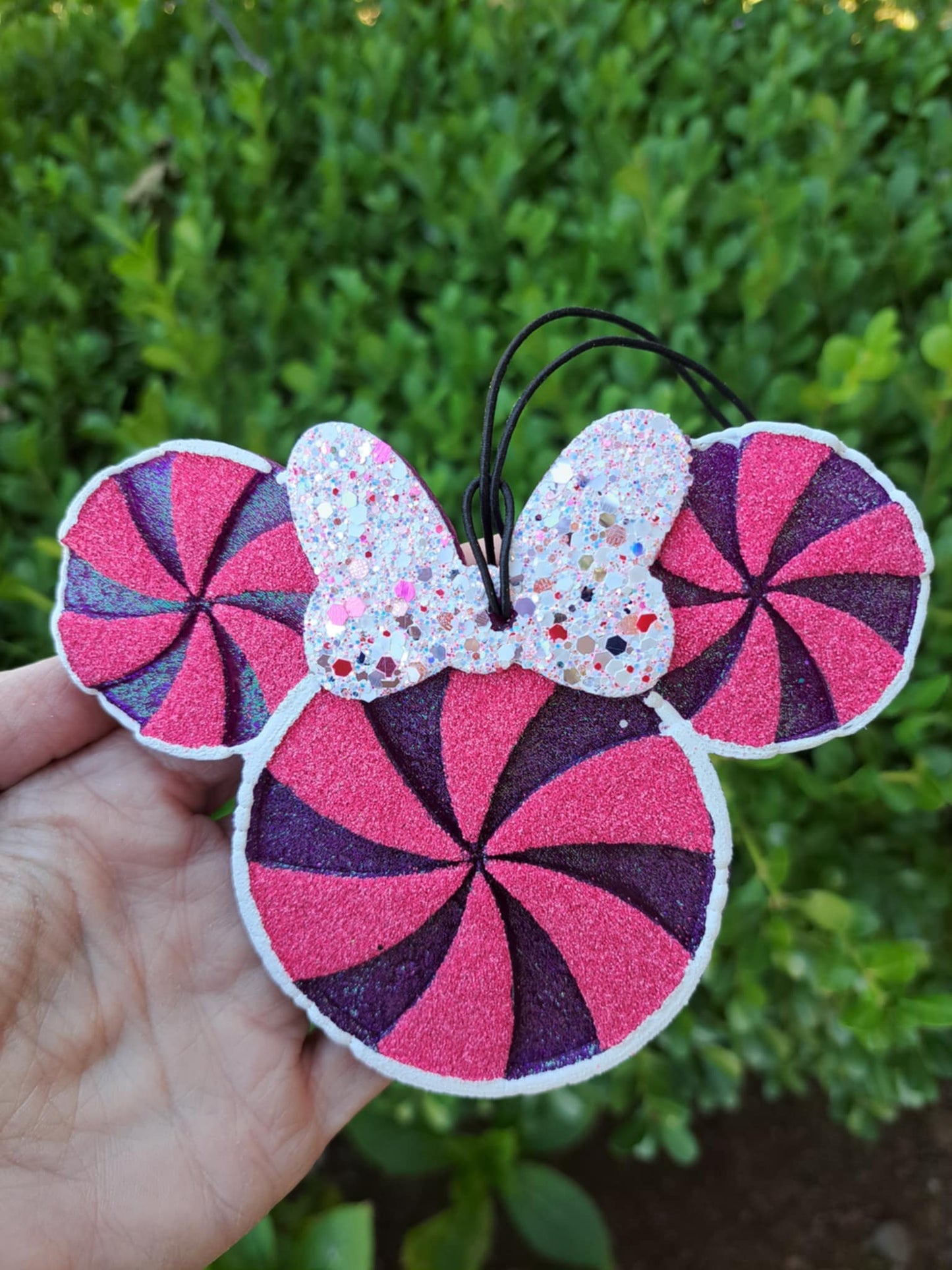 Pink and purple candy swirl design freshie with a bow held against a green leafy background