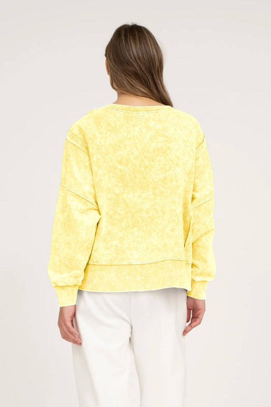 back view of a woman wearing a yellow acid washed top on a netural background