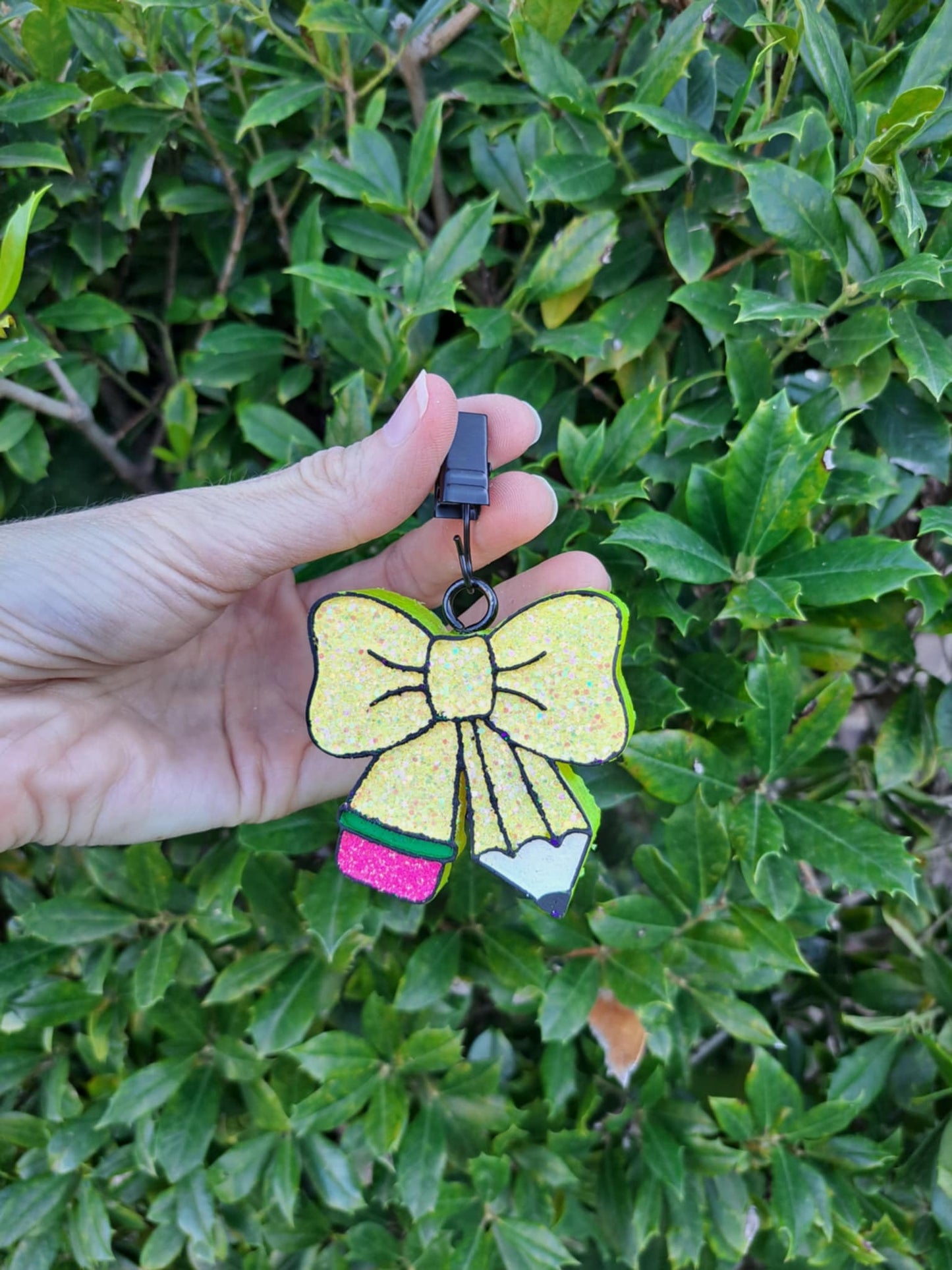 yellow pencil bow freshie held against a green leafy background
