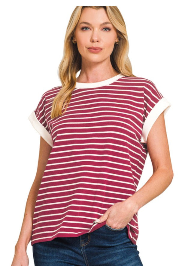 Woman wearing a cabernet red and white striped shirt with blue jeans on a white background