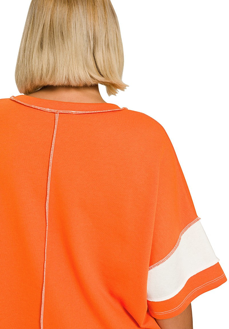 A close-up back view of a person wearing an orange short-sleeve top with a white sleeve stripe and a vertical seam down the back, on a white background.