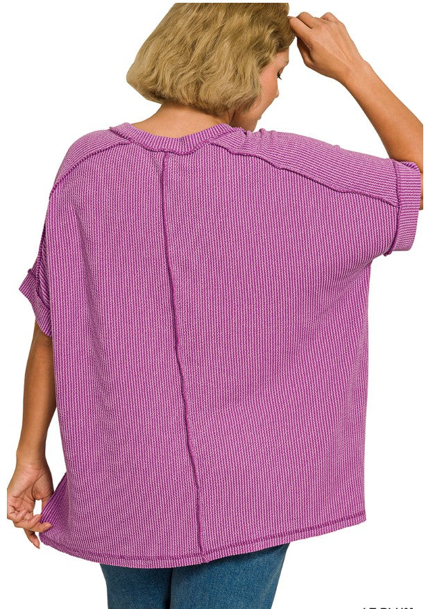 Person wearing a purple textured top with short sleeves on a white background